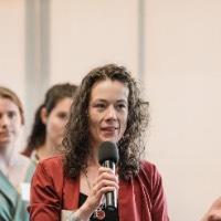 Woman speaking to crowd holding a microphone